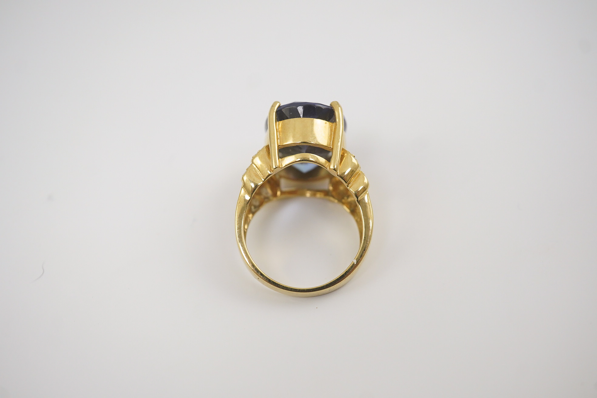 A modern 18ct gold and single stone oval cut tanzanite set dress ring, with eight stone diamond chip set shoulders